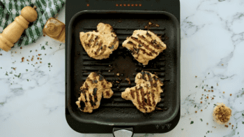 4 grilled chicken thighs in a grill pan.