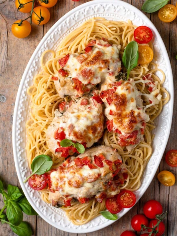 overhead shot of bruschetta chicken on top of pasta on plate