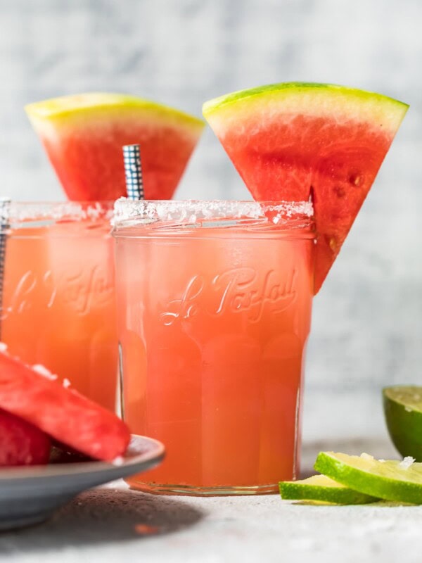 two watermelon margaritas with sliced watermelons on top of the glasses