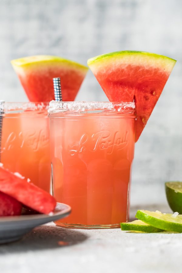 two watermelon margaritas with sliced watermelons on top of the glasses