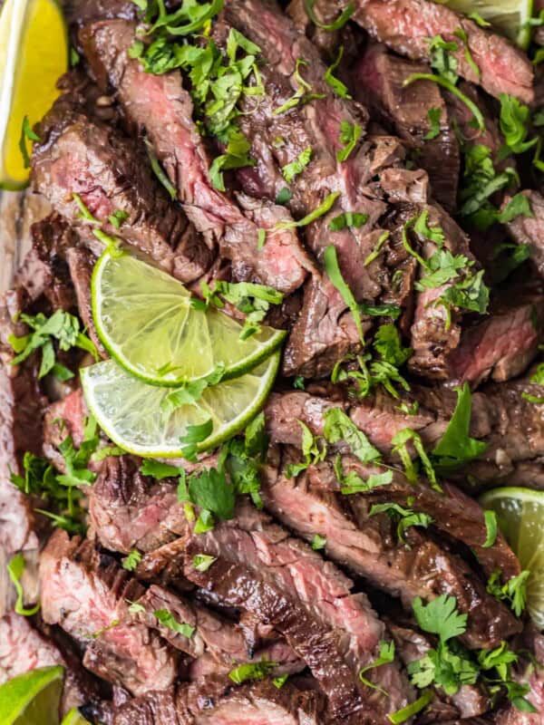 top shot of carne asada steak with sliced lime and cilantro