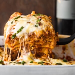 cheesy lasagna coming out of baking dish