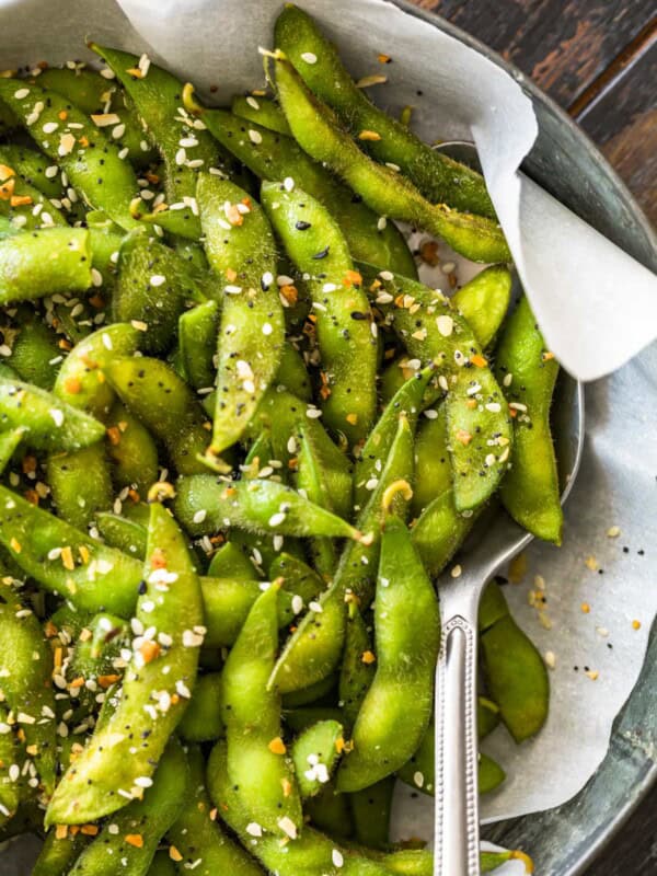 Bright green edamame in a bowl seasoned with a spoon