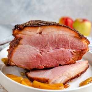 A side shot of a glazed ham with cooked apples