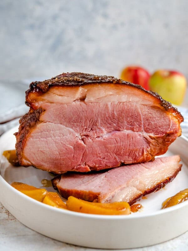 A side shot of a glazed ham with cooked apples