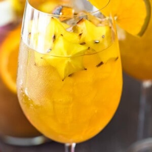 honey bourbon sangria in a wine glass with a sliced orange on the rim