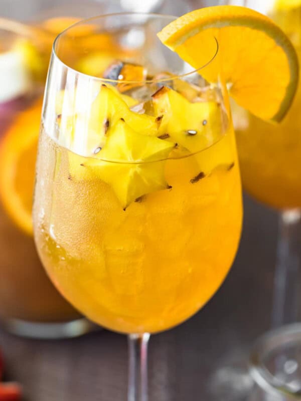 honey bourbon sangria in a wine glass with a sliced orange on the rim