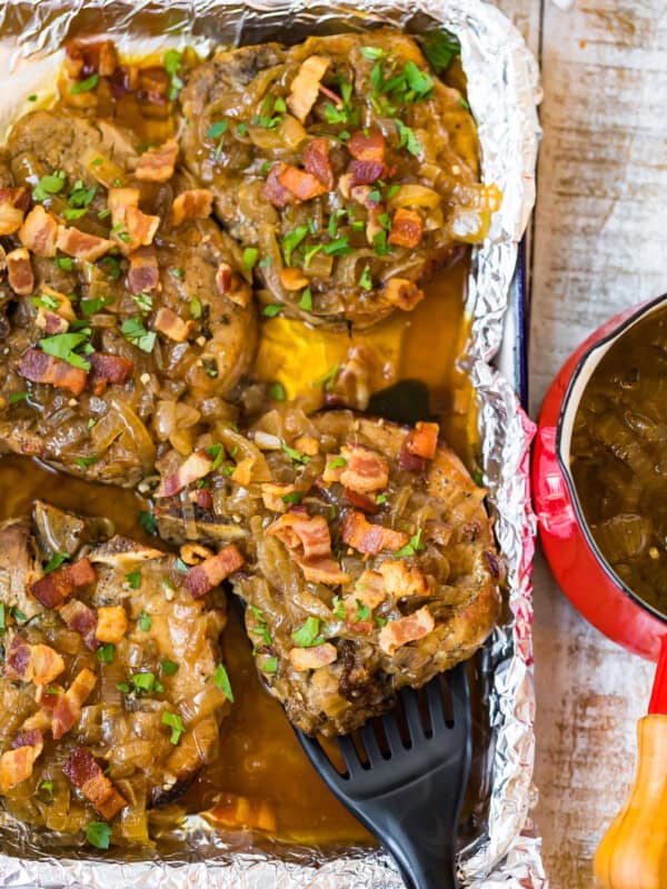 slow cooker smothered pork chops in a pan with a spatula lifting one out