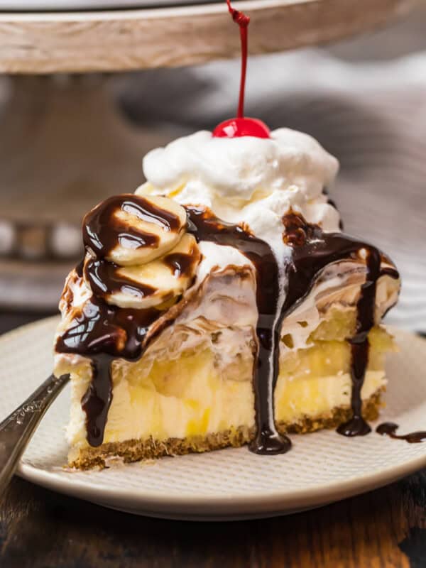 a slice of banana split cake on a plate drizzled in chocolate syrup