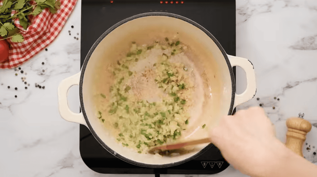 sautéeing onion, jalapeno, and garlic in a dutch oven with a wooden spatula.