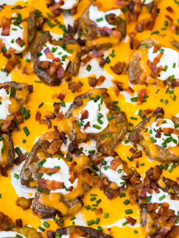 a pan of loaded smashed potatoes covered in cheese and bacon