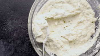 seasoned ricotta cheese in a glass bowl with a spoon.