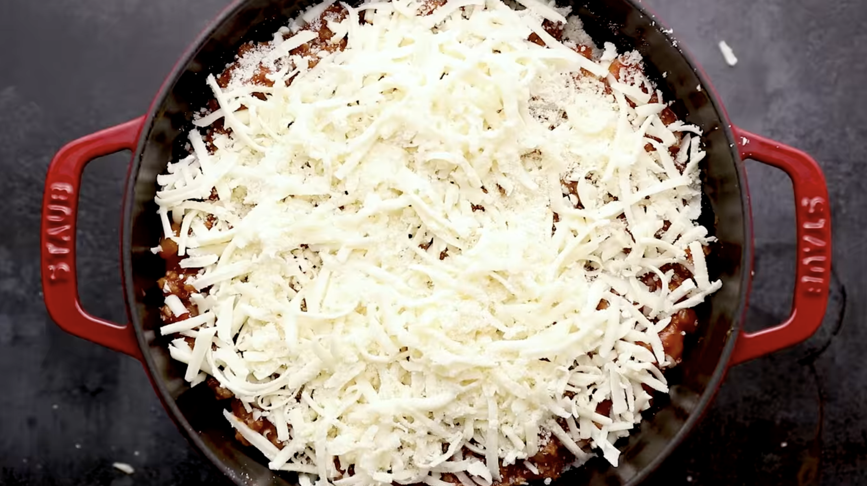 overhead view of cheese-topped lasagna in a dutch oven.