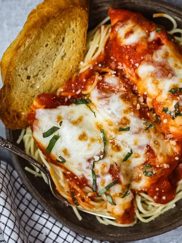 a bowl of chicken parmesan with a slice of bread