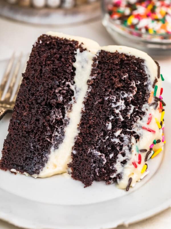 A piece of chocolate cake on a plate, with Icing and Cookie