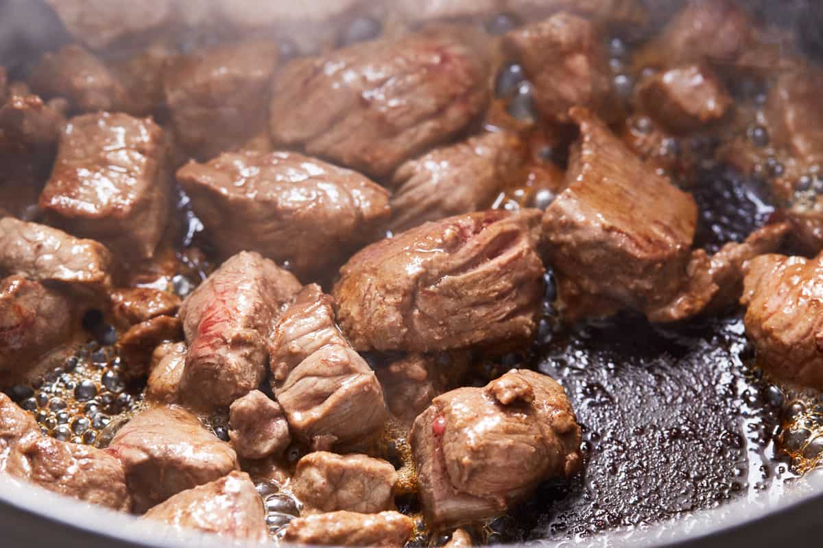 Cubes of beef browning in a pan.