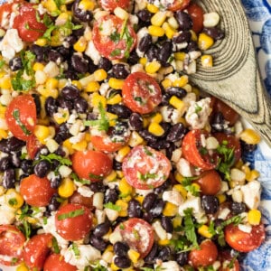 tomato corn salad on platter with wooden spoon