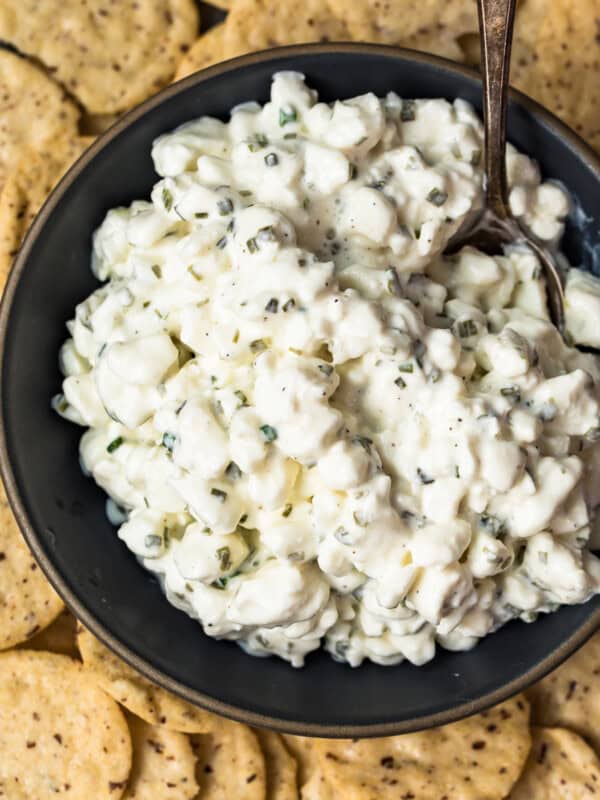 up close image of herbed cottage cheese in bowl surrounded by crackers