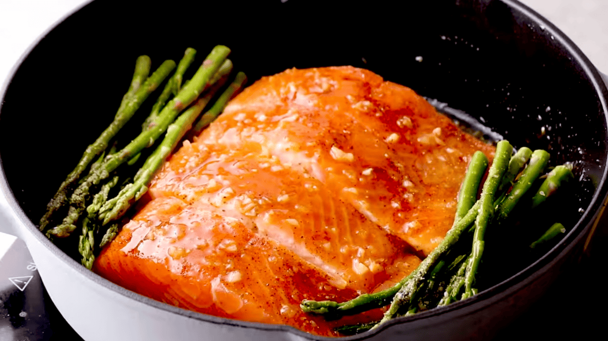 4 salmon fillets and asparagus in a pan.