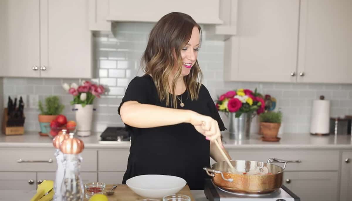 a woman in a black shirt is stirring a pot on a stove.