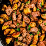 garlic steak bites with potatoes in skillet