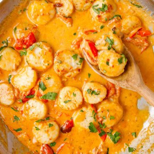 creamy garlic scallops in skillet with wooden spoon