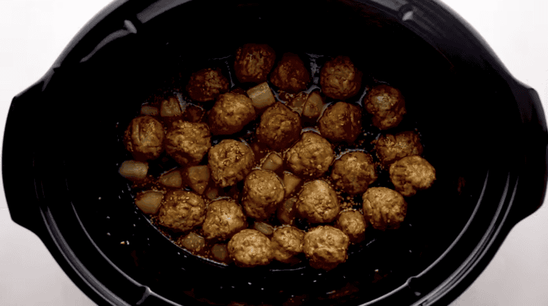 saucy meatballs and pineapple chunks in a crockpot.