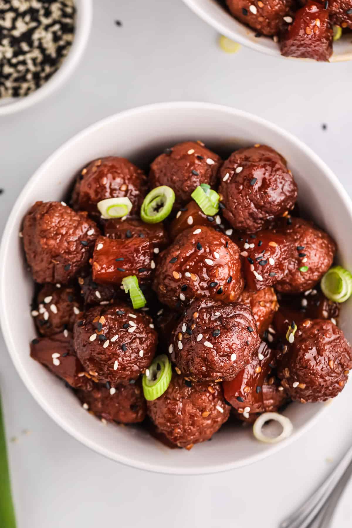 Crockpot teriyaki meatballs in white bowl.