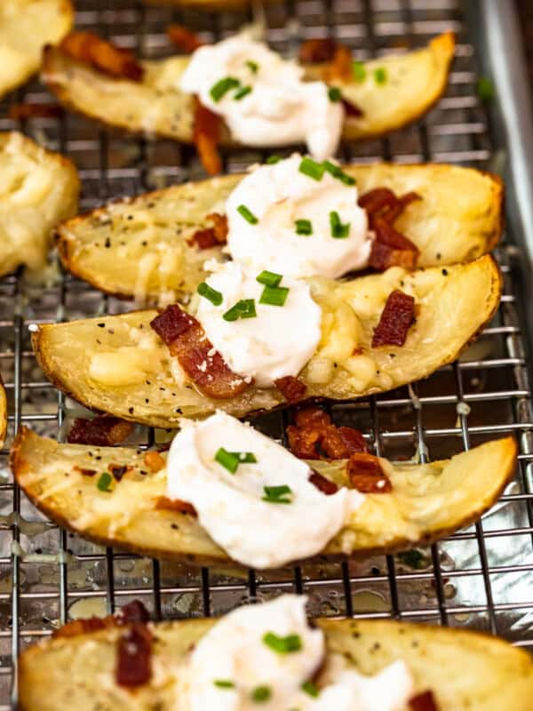 up close side shot potato skins on baking sheet with sour cream, bacon, and chives