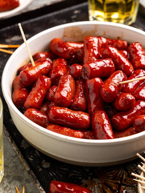 little smokies sausages in a white bowl with toothpicks.