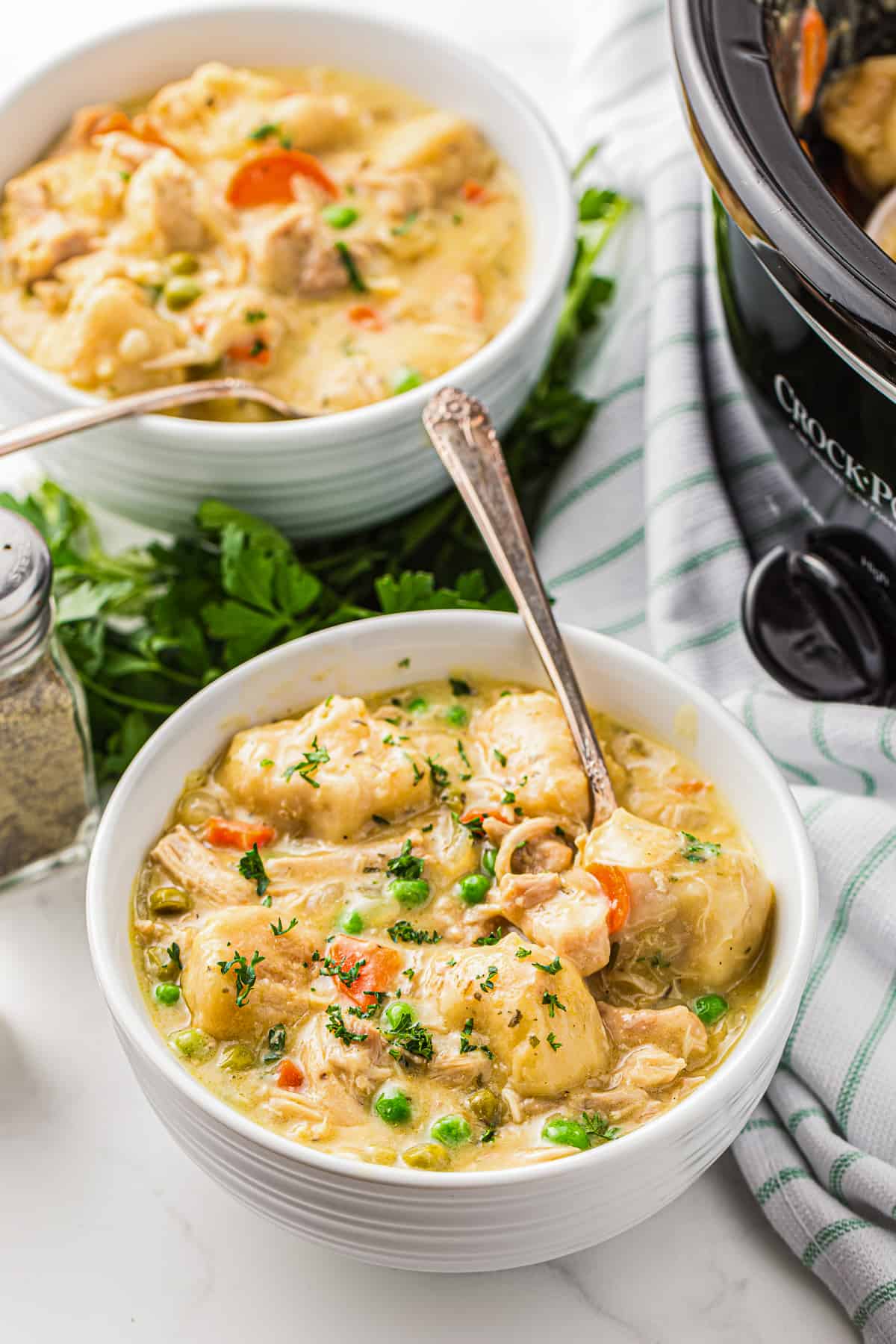 two bowls of chicken and dumplings made in crockpot with spoons