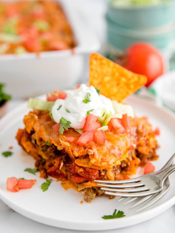 slice of dorito casserole garnished with sour cream and chopped tomatoes