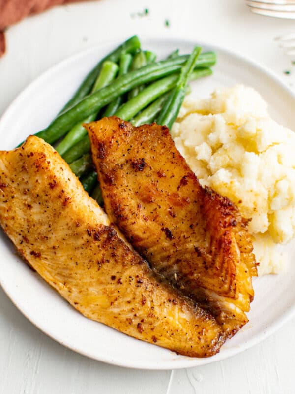 pan fried tilapia on plate with green beans and mashed potatoes