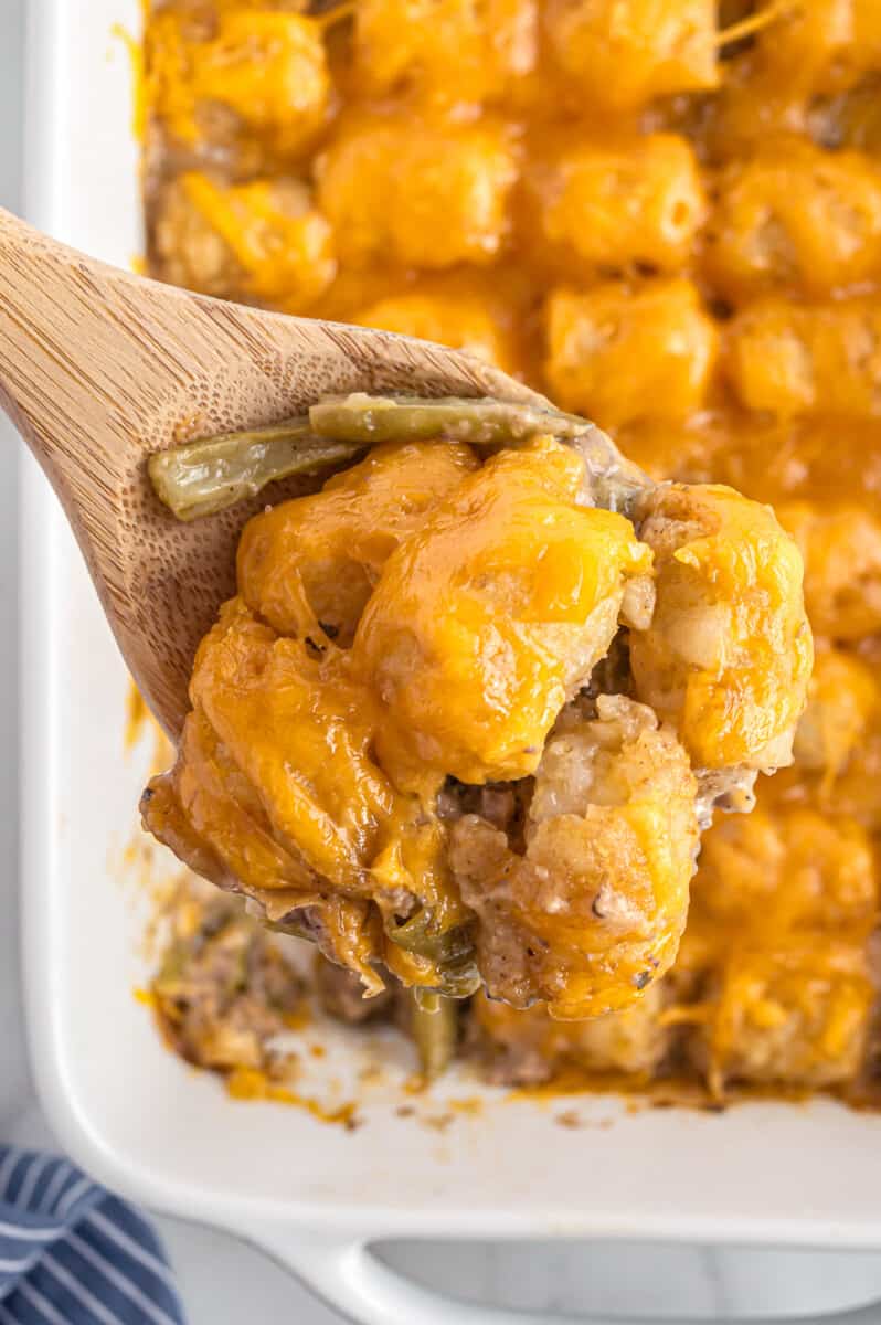 lifting up wooden spoon with tater tot casserole