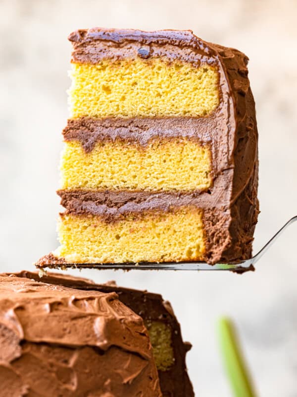 lifting up slice of yellow layer cake with milk chocolate frosting