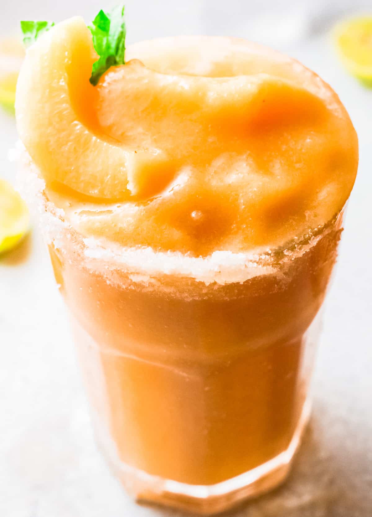 salt rimmed glass with frozen peach margarita