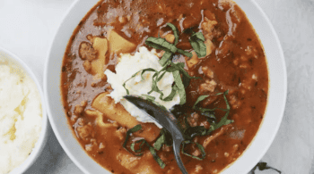 overhead view of a bowl of lasagna soup topped with ricotta and basil.