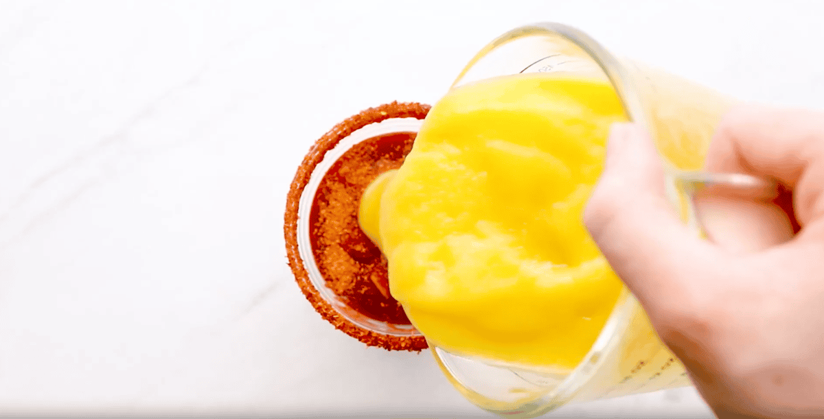 layering mango and chamoy in a cup.