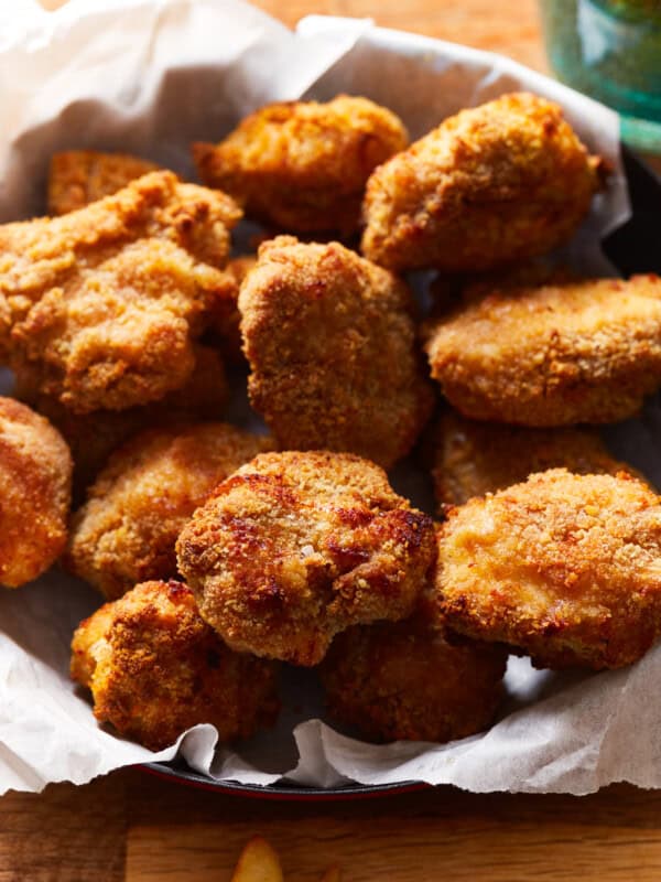 air fryer chicken nuggets in a parchment lined basket.