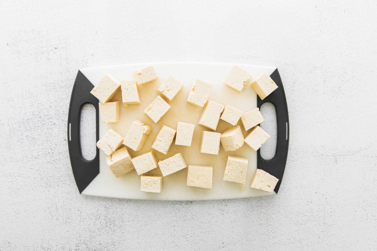 cubes of tofu for air fryer teriyaki tofu on a plastic cutting board.