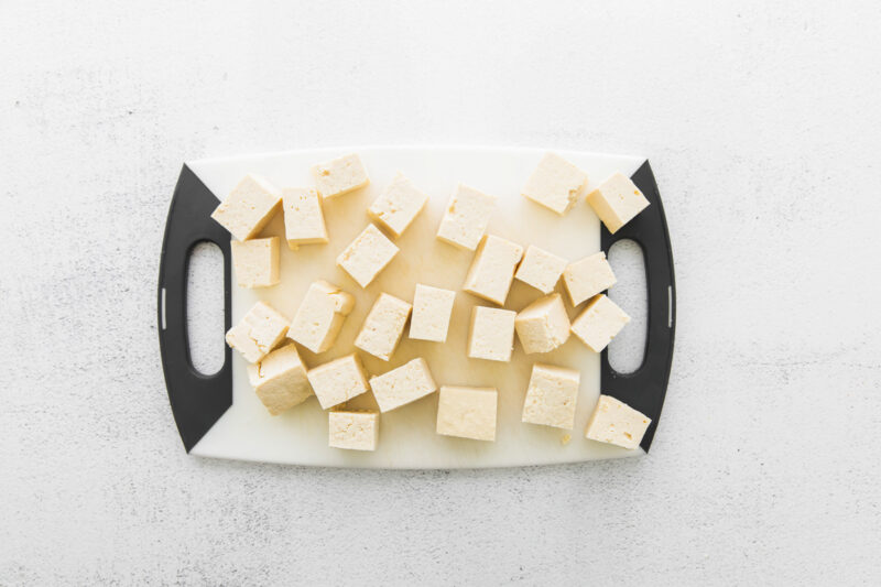 cubes of tofu for air fryer teriyaki tofu on a plastic cutting board.