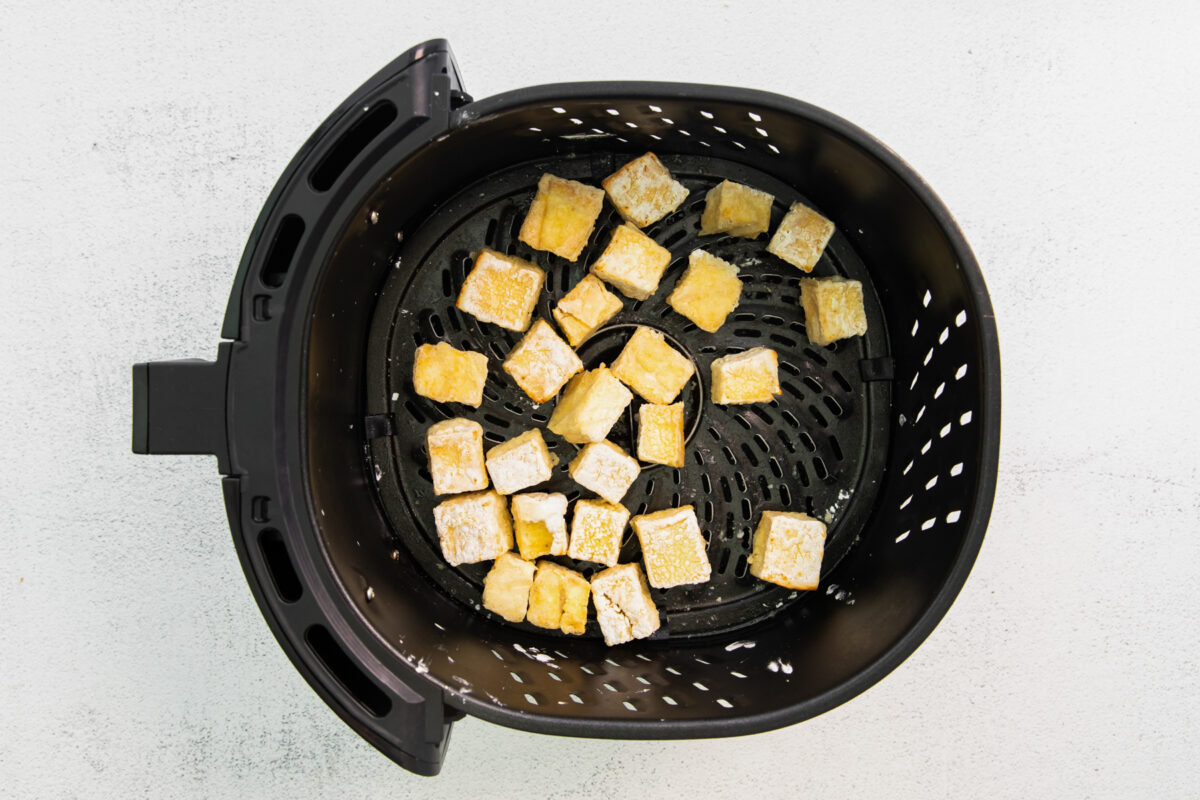 cubes of cooked air fryer teriyaki tofu in an air fryer basket.