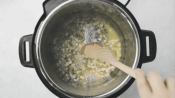 sautéing onion and jalapeno in an instant pot with a wooden spoon.