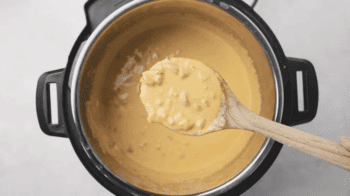 lifting a spoonful of queso from an instant pot.