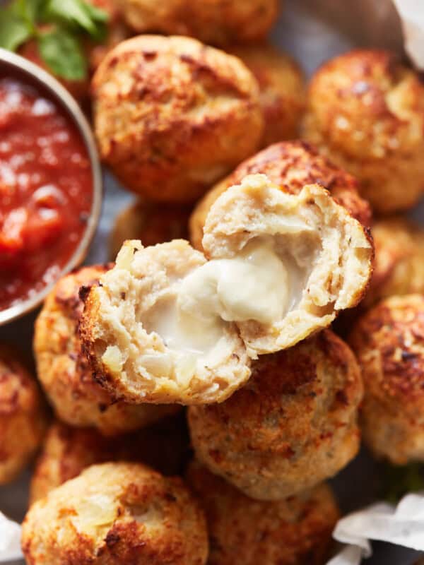 a halved baked turkey meatball on top of a pile of meatballs.