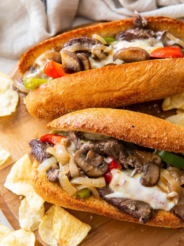 two philly cheesesteaks on cutting board