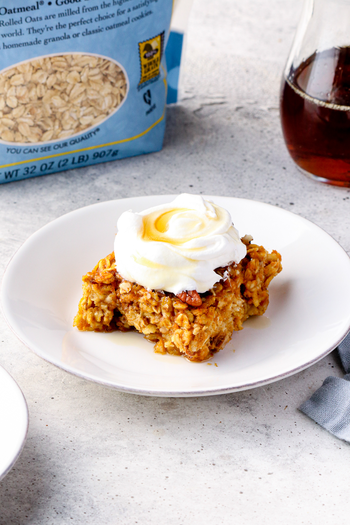 slice of pumpkin pie baked oatmeal with whipped cream and maple syrup.