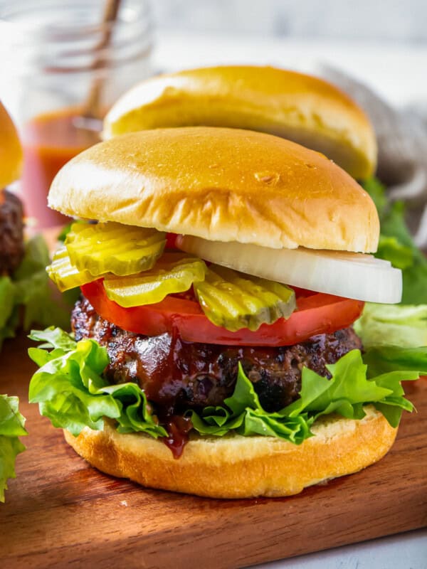 up close grilled bbq burgers with lettuce, tomato, onion, and pickles