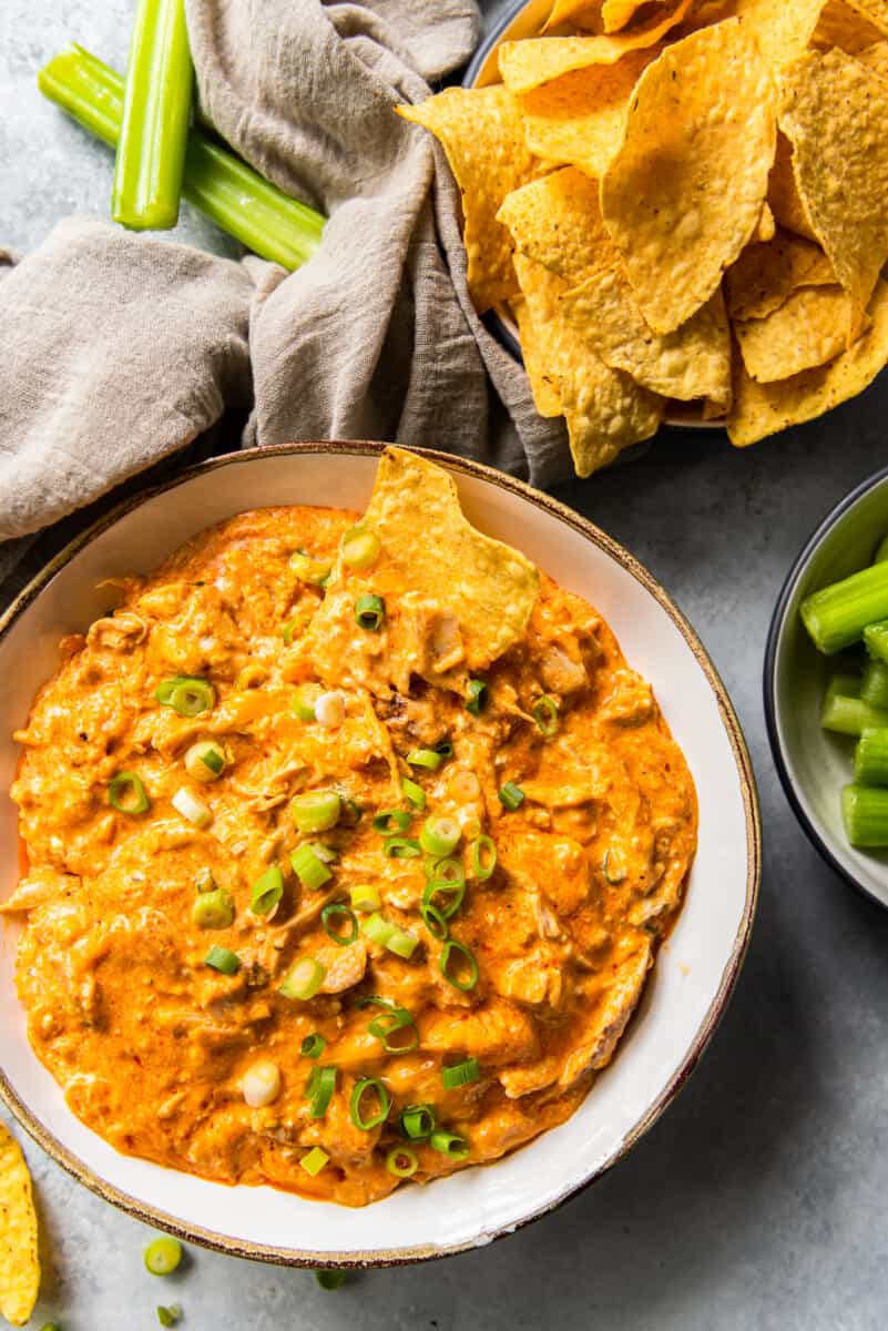 bowl of chips next to crockpot buffalo chicken dip