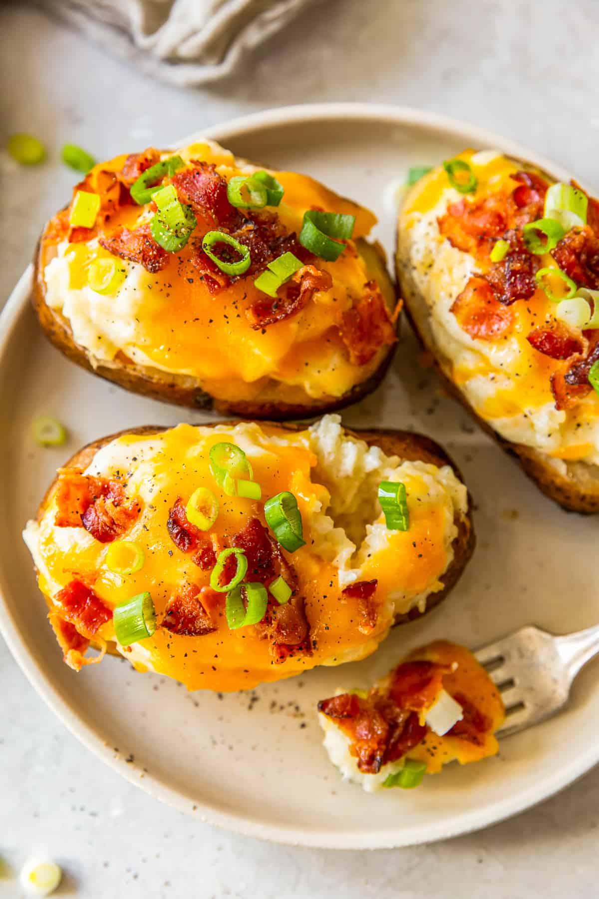 three crockpot twice baked potatoes on white plate with fork